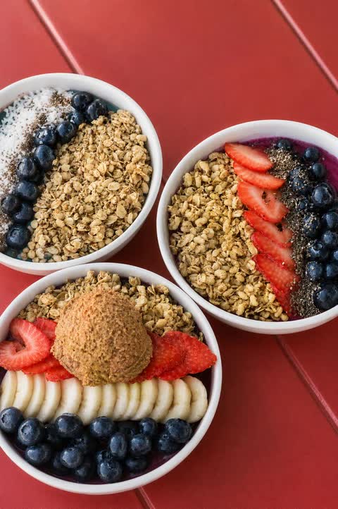 Three smoothie bowls topped with granola, strawberries, blueberries and banana
