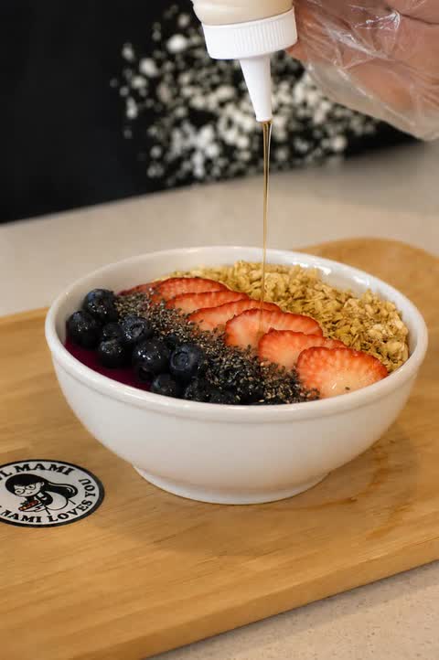Honey drizzled over a smoothie bowl with blueberries, strawberries, chia seeds and granola